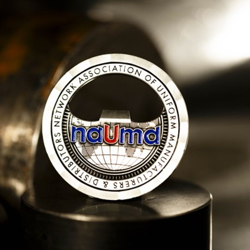 Custom NAUMD challenge coin in antique silver finish, with the NAUMD' logo in the centre. The logo is coloured with enamel. The coin has a cut out in the centre that doubles as a beer bottle opener. 