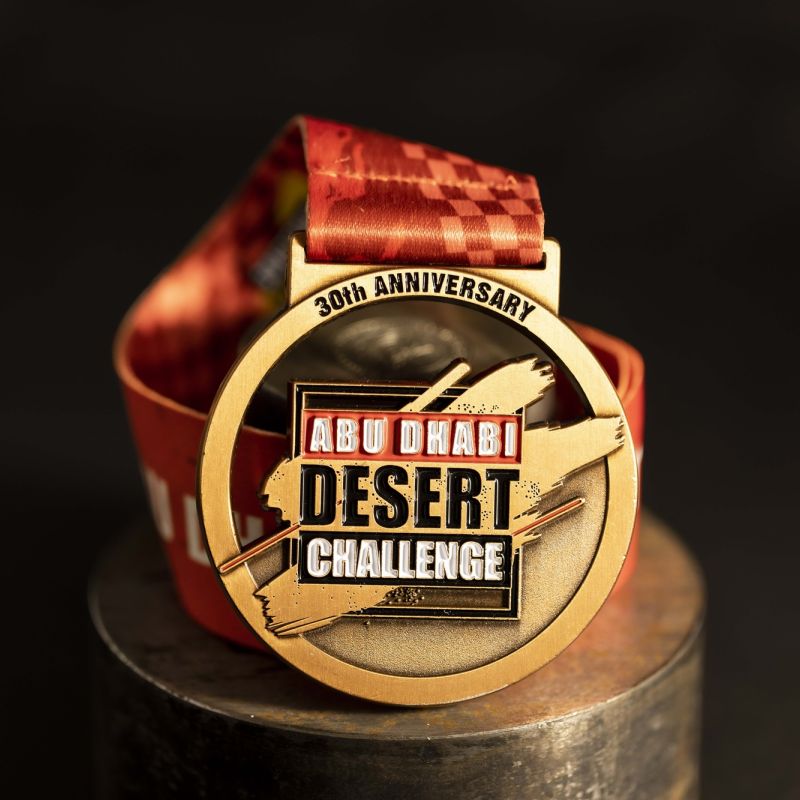Metal Abu Dhabi Desert Challenge '30th Anniversary' custom event medal with an antique gold finish. The event's logo is coloured in with enamel. The medal features distinctive cut outs.