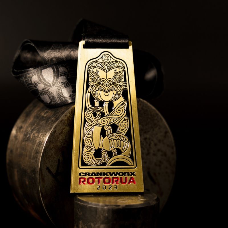 Metal Crankworx Rotorua custom event medal with an antique silver finish. The event's logo is coloured in with enamel. The medal features distinctive cut outs and a custom shape..