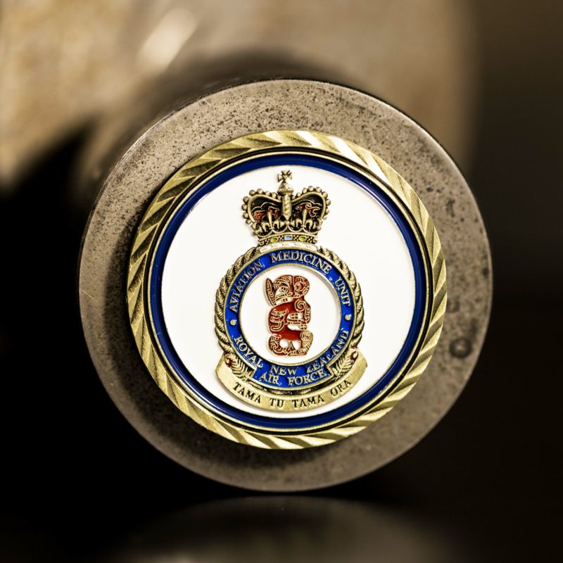 Custom Royal New Zealand Air Force (RNZAF) challenge coin in antique gold finish, with the unit's logo in the centre. The logo is coloured with enamel. The challenge coins has oblique line edges.