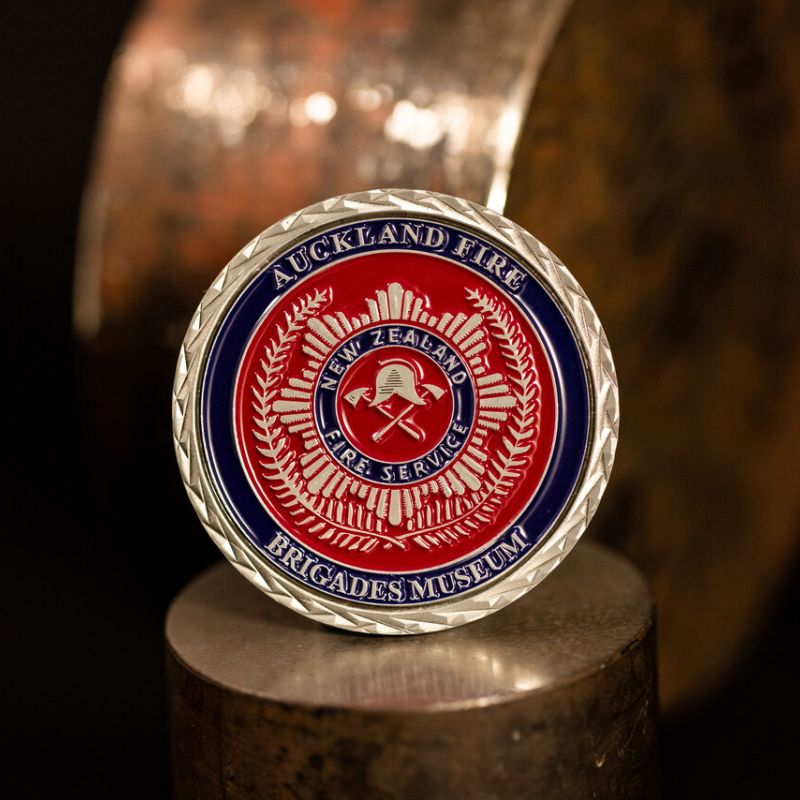 Custom Auckland Fire Brigade Museum challenge coin in antique silver finish, with a custom design in the centre. The logo is coloured with enamel. 