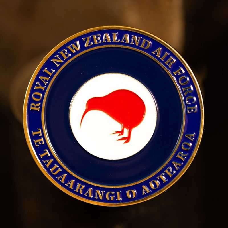 Custom Royal New Zealand Army 'Logistic Regiment' challenge coin in antique gold finish, with the unit's logo in the centre. The logo is coloured with enamel. The edge of the coin has oblique lines.