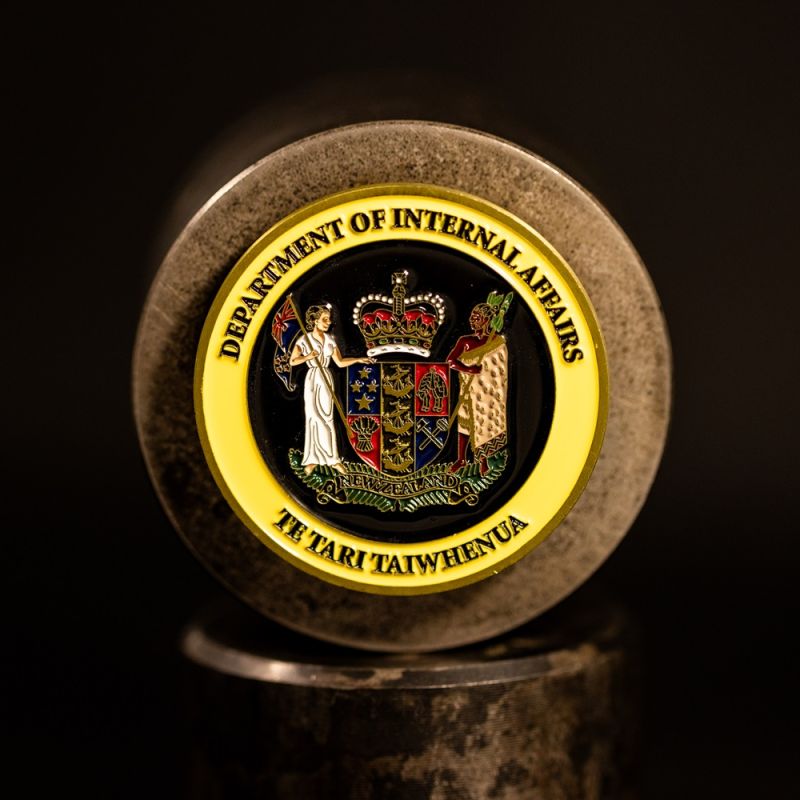 Custom Department Of Internal Affairs challenge coin in antique gold finish, with a custom design in the centre. The logo is coloured with enamel. 