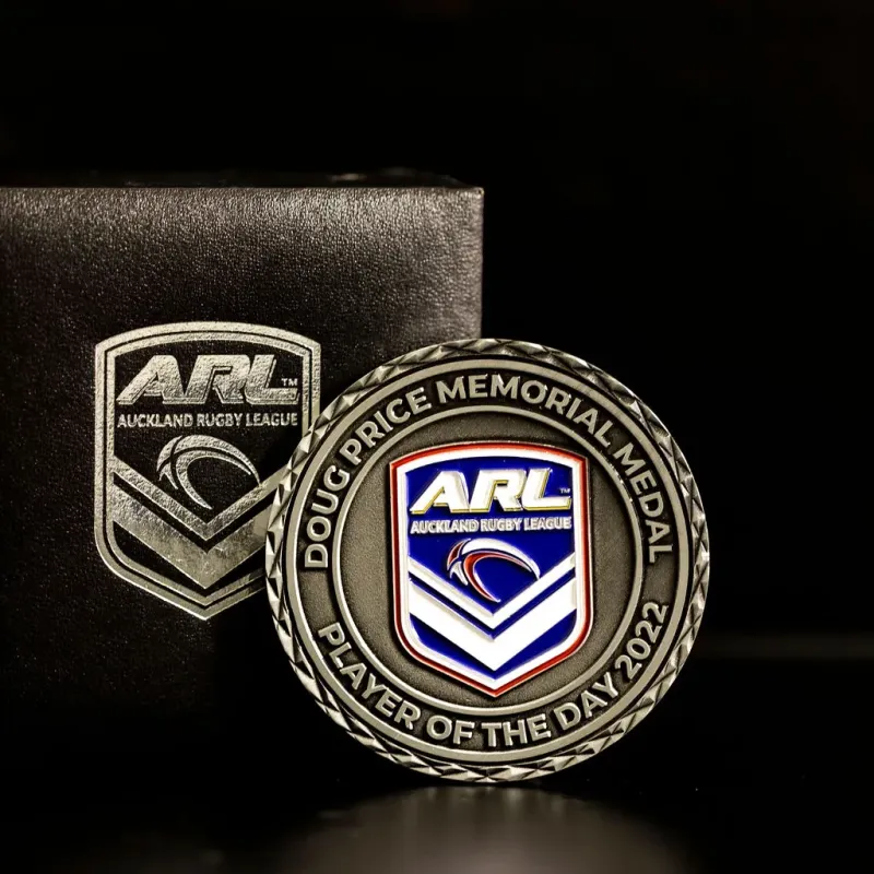 Custom Auckland Rugby League challenge coin in antique silver finish, with the league's logo in the centre. The logo is coloured in with enamel. The words 'Player Of The Day 2022' circle the logo. The coin features cross-cut edges. It comes with a custom leather display box.