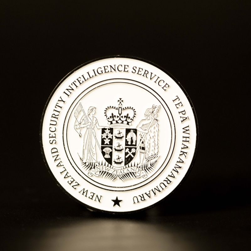 Custom Royal New Zealand Army 'Logistic Regiment' challenge coin in antique gold finish, with the unit's logo in the centre. The logo is coloured with enamel. The edge of the coin has oblique lines.