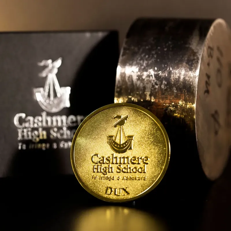 Custom Cashmere High School DUX challenge coin in antique gold finish, with the school's logo in the centre of each. The challenge coins comes with a custom cardboard display box.