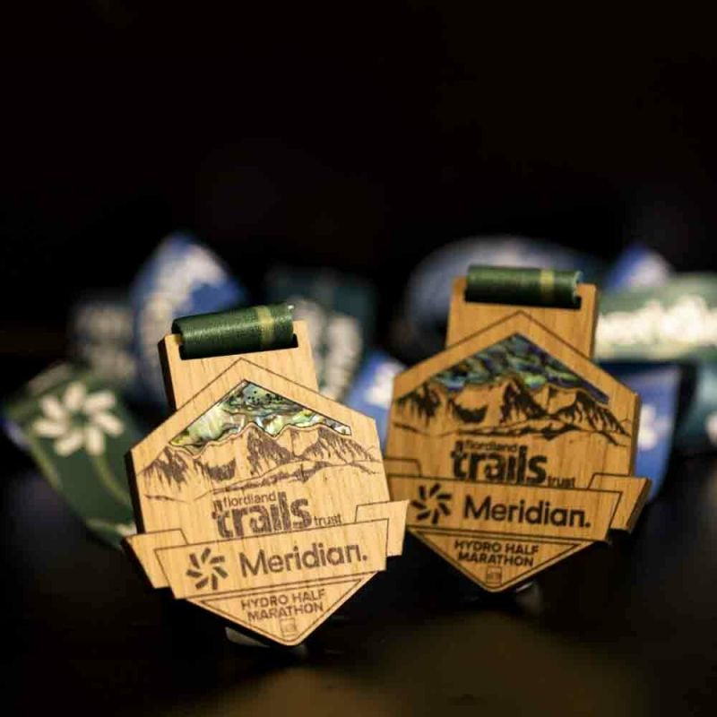 Wooden Meridian Half Marathon custom event medal. The event's logo is laser engraved onto the wood. The medal features custom paua shell detailing.