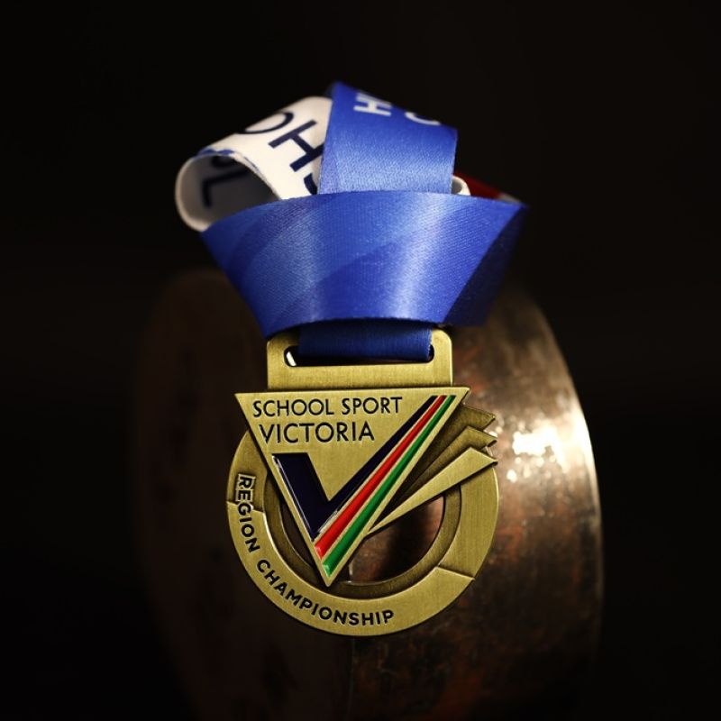Metal Nike Melbourne Marathon custom event medal with antique gold finish. The marathon's logo is coloured in with enamel. The medal features a cut out that doubles as a bottle opener in its centre. 