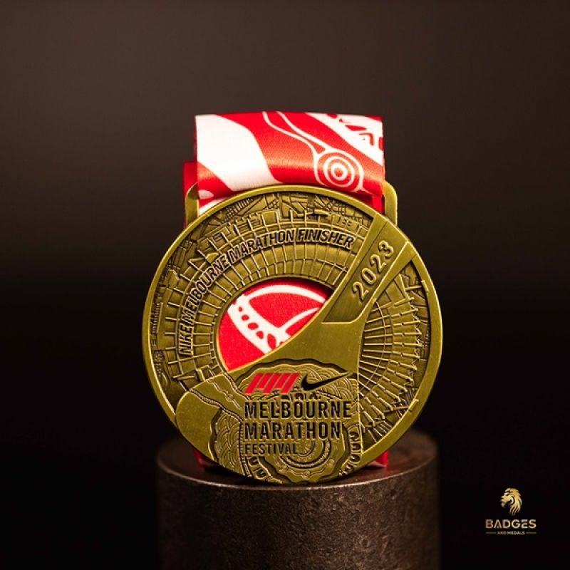 Metal Nike Melbourne Marathon custom event medal with antique gold finish. The marathon's logo is coloured in with enamel. The medal features a cut out that doubles as a bottle opener in its centre. 