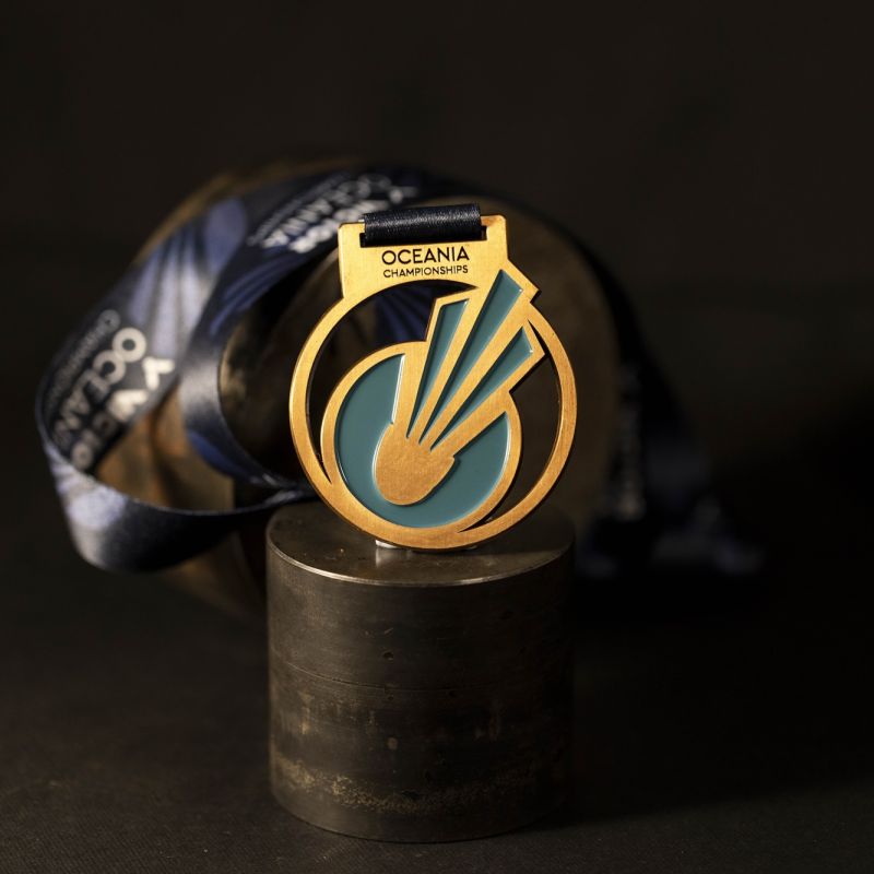 Metal Oceania Badminton custom event medal with an antique copper finish. The event's logo is coloured in with enamel. The medal features several cut outs to elevate its design.